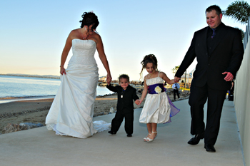 Leisha and Jeff walk along Moreton Bay at Woody Point with their children after their wedding